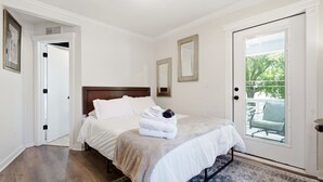 Un dormitorio con una cama, una puerta, un ventanal y una alfombra.