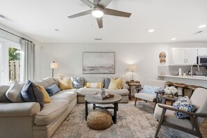 A modern living room with a ceiling fan, a sofa set, a coffee table, and a kitchen area with cabinets and a microwave. - Minutes to Wrightsville Beach, Downtown & UNCW (Wilmington)