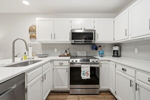 Uma cozinha moderna com armários brancos, eletrodomésticos de aço inoxidável e painel de azulejos.