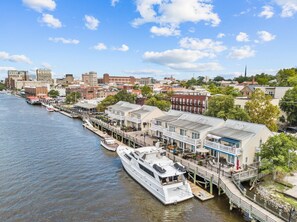 A waterfront hotel with a dock, a large white boat, and a row of buildings along the river. - Minutes to Wrightsville Beach, Downtown & UNCW (Wilmington)