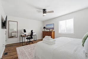 A bedroom with a bed, desk, chair, and a ceiling fan. - Minutes to Wrightsville Beach, Downtown & UNCW (Wilmington)