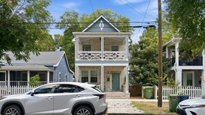 A two-story house with a balcony, a driveway, and a white SUV parked in front. - The Jade Getaway in Historic Castle St. District (Wilmington)
