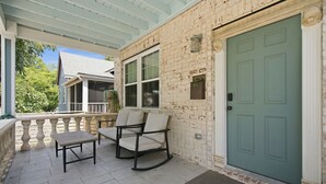 A covered porch with a bench and chairs, a mailbox, and a green door. - The Jade Getaway in Historic Castle St. District (Wilmington)