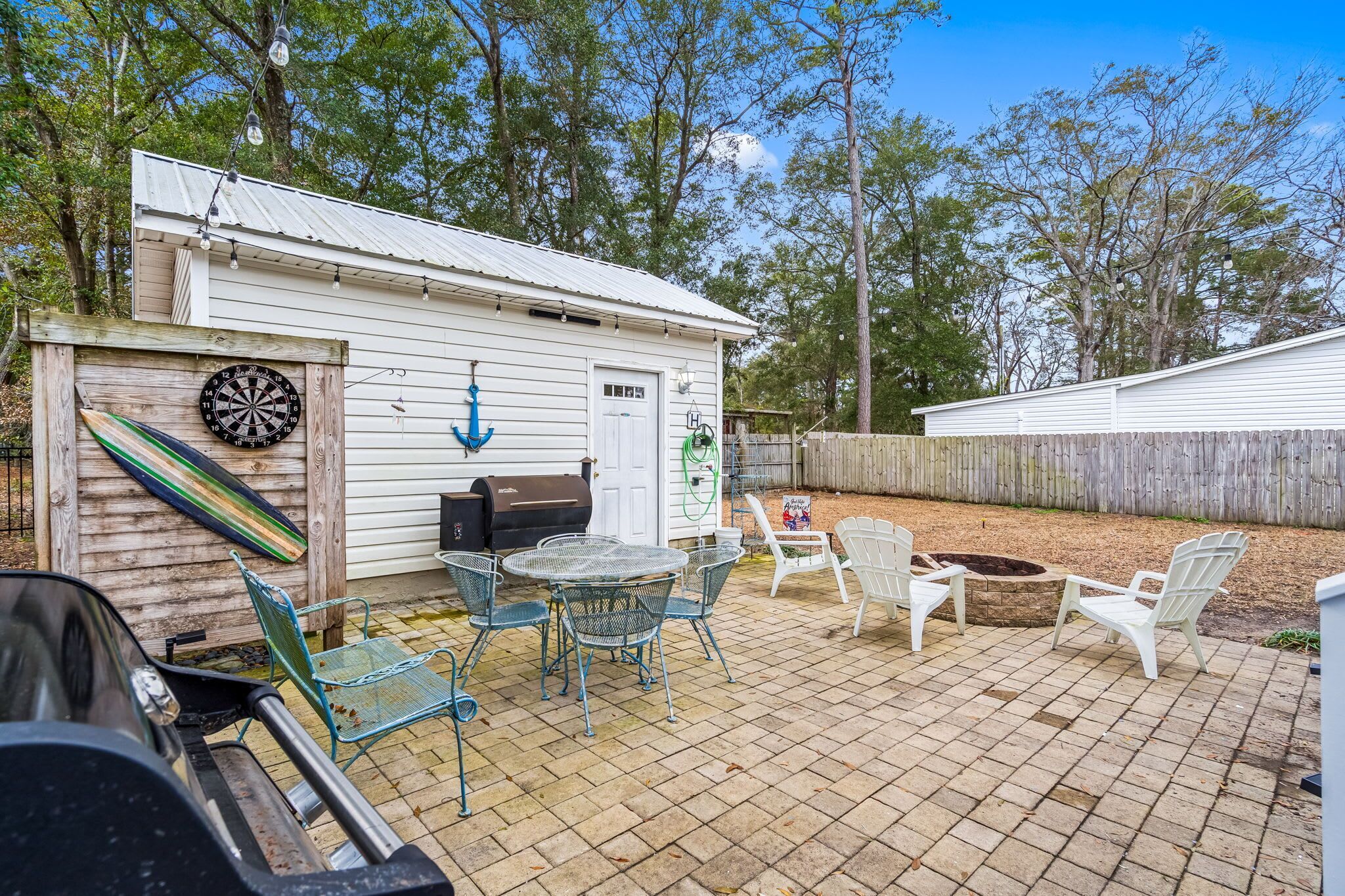 Un espace patio avec des sièges d’extérieur, un barbecue et un jeu de fléchettes.