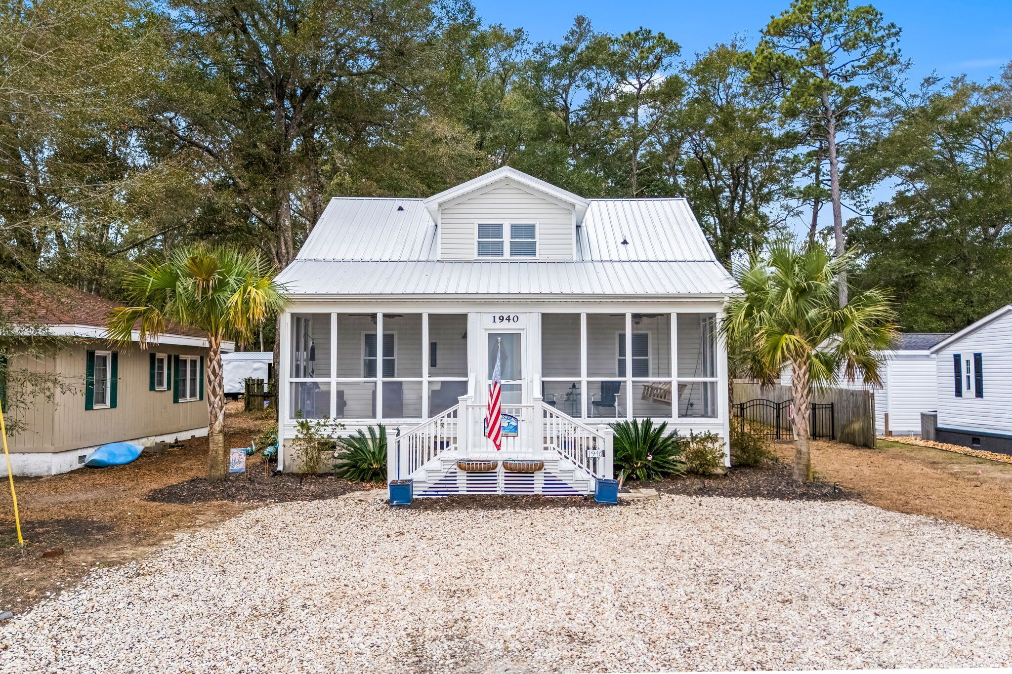 A single-story house with a front porch, a flag, and a year number on the door.