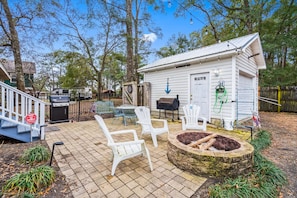 A backyard with a barbecue grill, outdoor seating, and a small shed with a door. - Cozy Beach Cottage Near Ocean Isle Beach (Ocean Isle Beach)