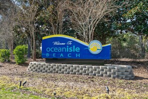 A welcome sign for Oceanisle Beach with a sun emblem. - Cozy Beach Cottage Near Ocean Isle Beach (Ocean Isle Beach)