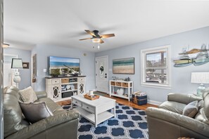 A living room with a television, a ceiling fan, a coffee table, and two sofas. - Cozy Beach Cottage Near Ocean Isle Beach (Ocean Isle Beach)