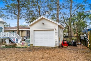 Une maison de plain-pied avec un garage, une véranda à l’avant avec des sièges d’extérieur et une petite terrasse.
