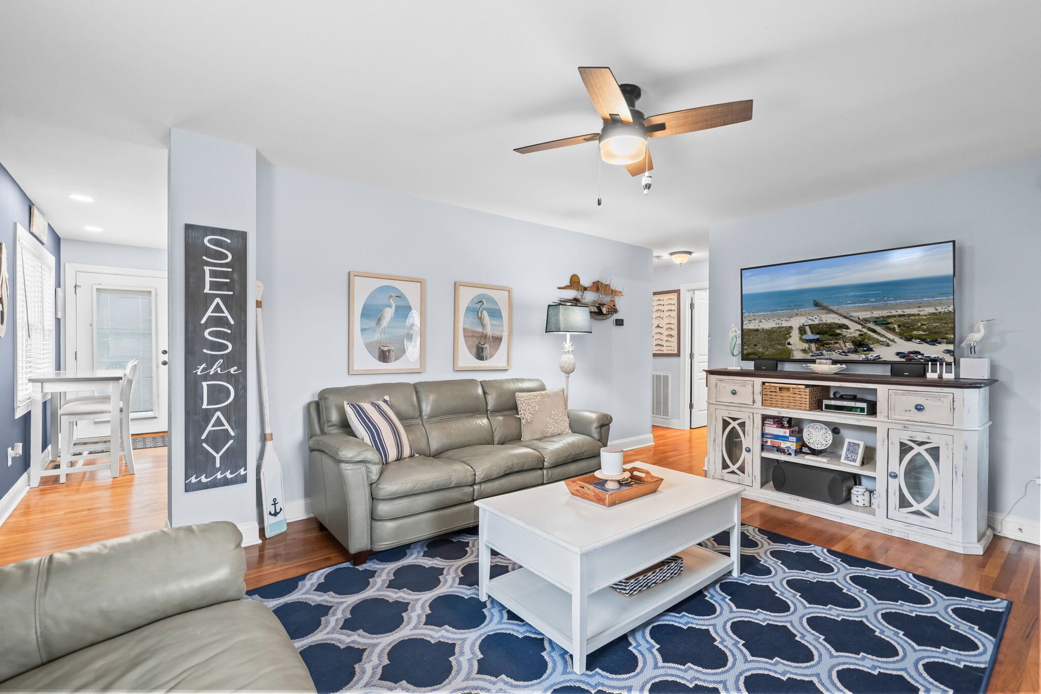 A living room with a grey sofa, a white coffee table, and a television on a cabinet.