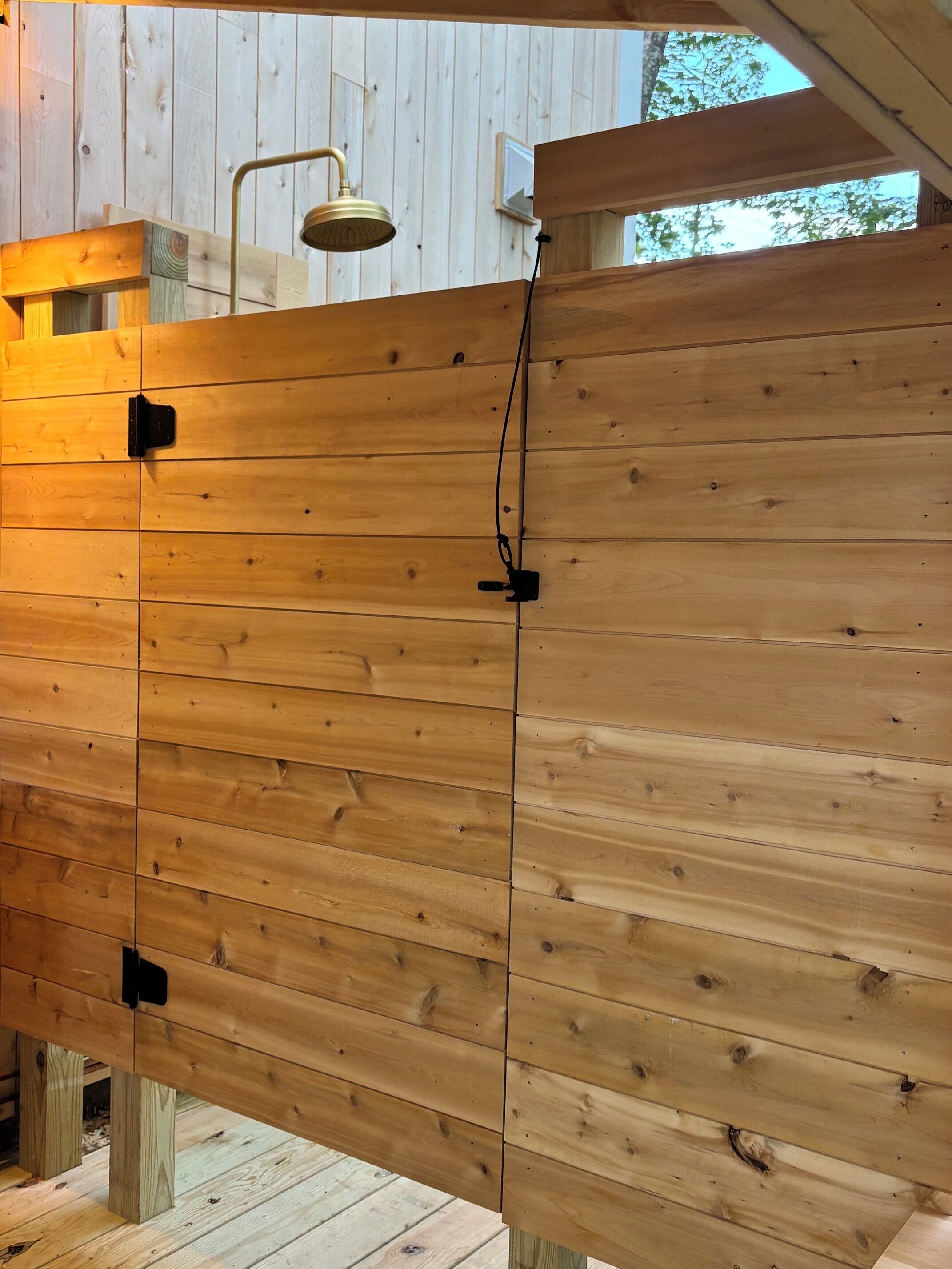 Eine Holzwand mit einer Duschbrause und einer Steckdose.
