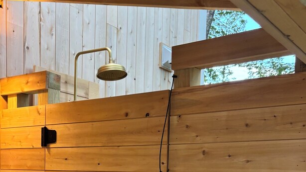 Eine Holzwand mit einer Duschbrause und einer Steckdose.