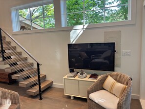 Ein modernes Wohnzimmer mit Treppe, Flachbildfernseher und einer gemütlichen Sitzecke.