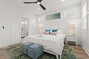 A bedroom with a bed, nightstands, a ceiling fan, and a painting on the wall. - Rooftop Spa + Bar | Walk to Beach | Sleeps 15! (Carolina Beach)