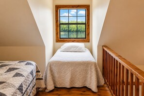A bedroom with a bed, a window with a view of greenery, and a wooden staircase. - White River Views, Covered Porch Cabin (Calico Rock)