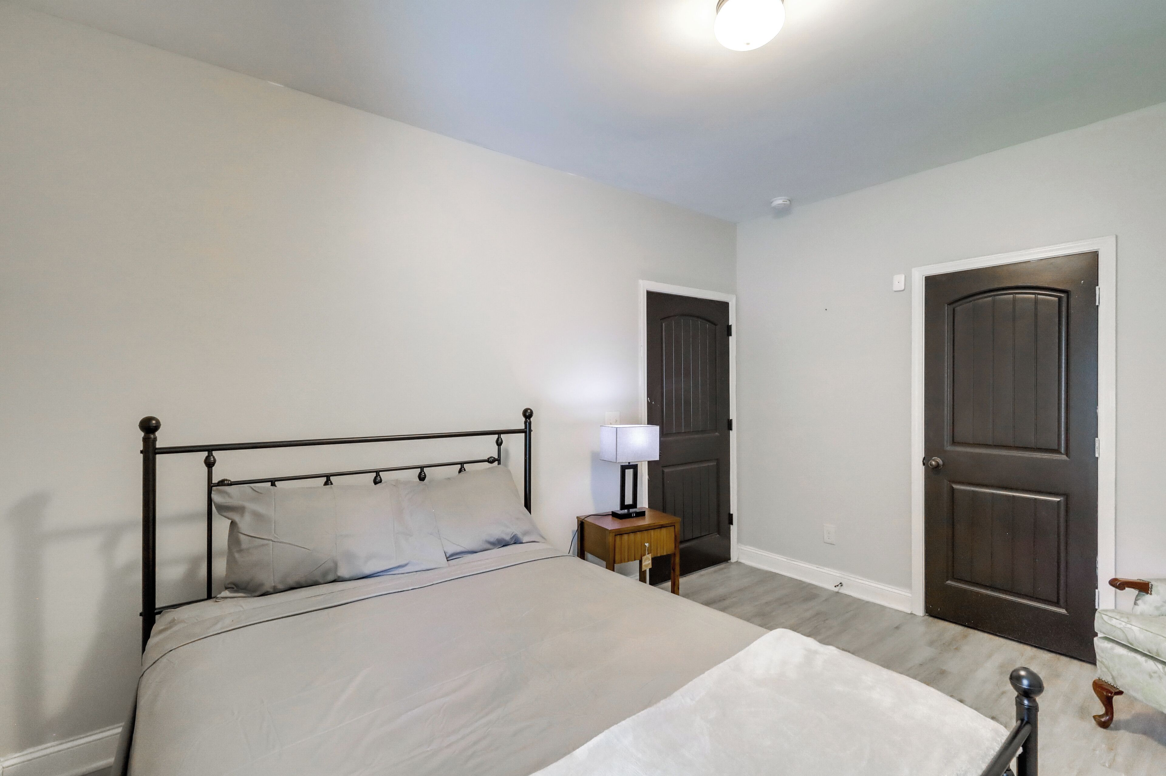 A bedroom with a bed, bedside table, lamp, and two doors.