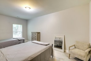 Une chambre avec deux lits, une chaise, une commode et un miroir.