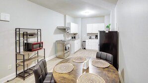 A compact kitchen with white cabinets, a microwave, and a stove. - Shop, Dine & Hike: Lawrenceville Home By Parks (Lawrenceville)