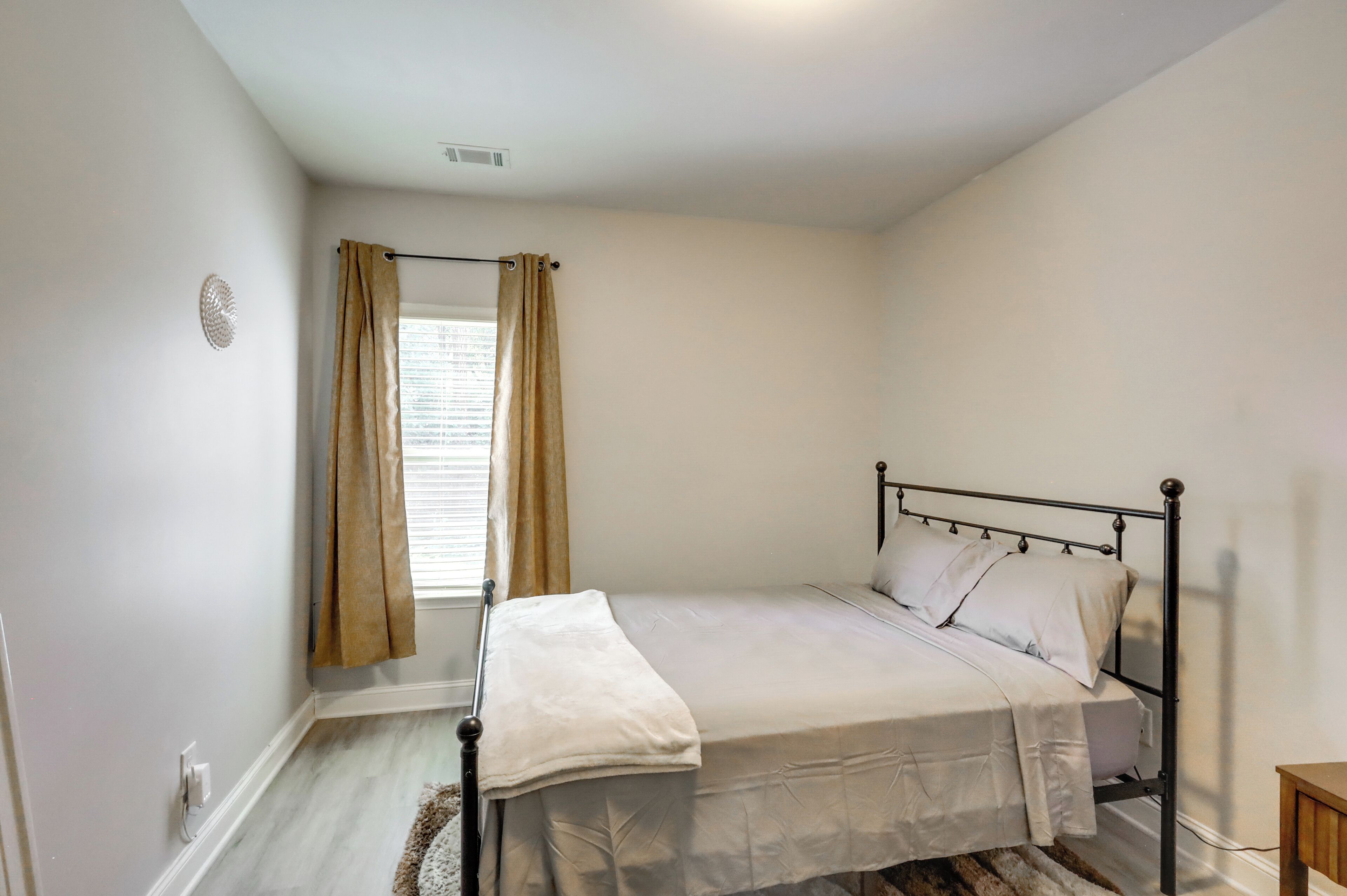 Ein Schlafzimmer mit Bett, Vorhängen, einem Fenster und einer Heizung.