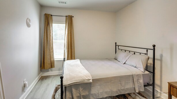 A bedroom with a bed, curtains, a window, and a radiator. - Shop, Dine & Hike: Lawrenceville Home By Parks (Lawrenceville)