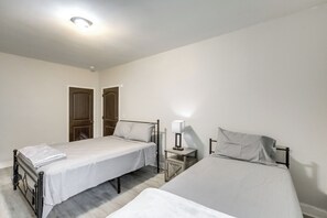 Ein Schlafzimmer mit zwei Betten, einem Nachttisch mit Lampe und einer Tür.