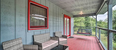 Eine überdachte Veranda mit Korbmöbeln und einem Glastisch.