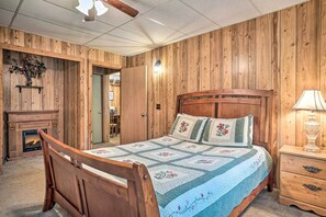 Ein Schlafzimmer mit Holzwandverkleidung, einem Bett, einem Nachttisch, einer Lampe und einem Kamin.