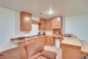 A compact kitchen with wooden cabinets, a countertop, a coffee maker, a toaster, and a white dishwasher.