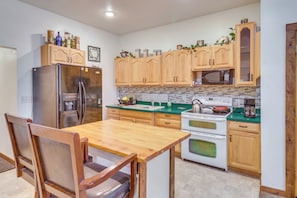 A kitchen with wooden cabinets, a stainless steel refrigerator, a microwave, and a stove.