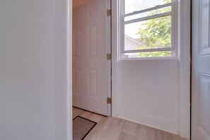 A white door with a window, a doormat, and a light-colored floor.