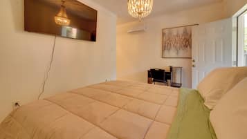 Un dormitorio con cama, candelabro, equipo de aire acondicionado, puerta y un cuadro en la pared.