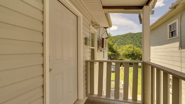 Eine überdachte Veranda mit Holzboden, weißem Außenputz und Blick auf eine grüne Landschaft.