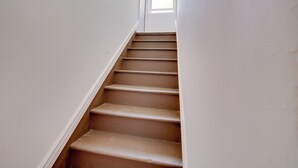 Eine Treppe mit weißen Wänden und einem Fenster am oberen Ende.