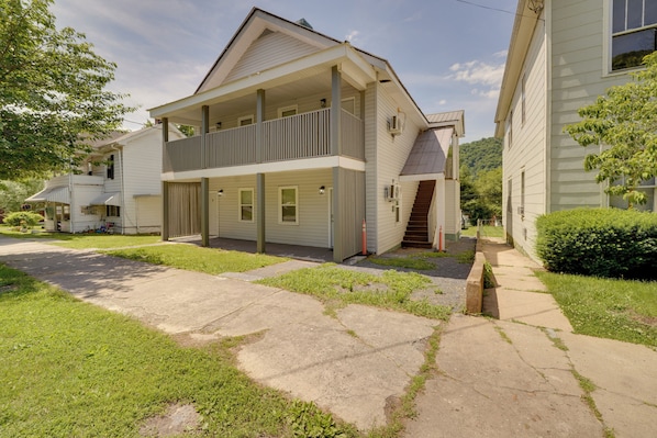 A two-story house with a balcony, a front porch, and a visible staircase leading to the entrance. - Walk to Dtwn Hinton: 2 Historic District Studios! (Hinton)