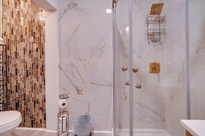 A bathroom with a glass-enclosed shower, a tiled mosaic wall, and a marble floor. - Walk to Dtwn Hinton: 2 Historic District Studios! (Hinton)