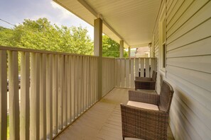 A covered porch with wicker furniture and a wooden railing.