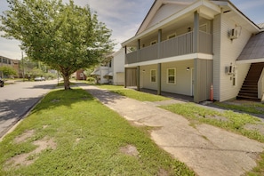 A two-story building with a balcony, a tree in front, and a sidewalk.