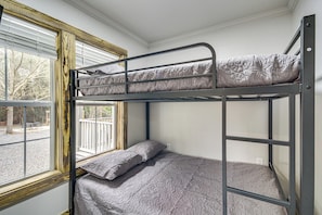 A bunk bed with a window view, a white wall, and a wooden window frame.