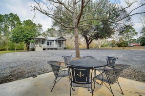 A house with a porch, a gravel driveway, and a table with chairs in front.