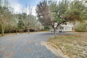 A house with a porch, surrounded by trees and a gravel driveway. - Group-Friendly Escape! Gateway to Gulfport Beaches (Gulfport)