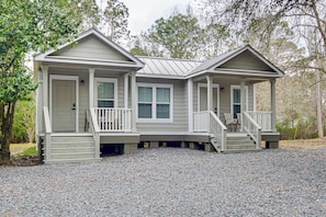 A two-story house with a front porch, a covered front entrance, and a gravel driveway.