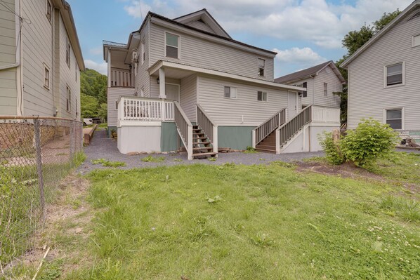A two-story residential building with a front porch, a staircase leading to the second floor, and a small front yard.