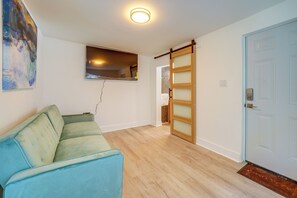 Une pièce avec un canapé bleu clair, une porte en bois et une petite fenêtre.