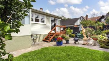 A residential property with a front yard, a wooden staircase leading to a door, and a variety of potted plants.