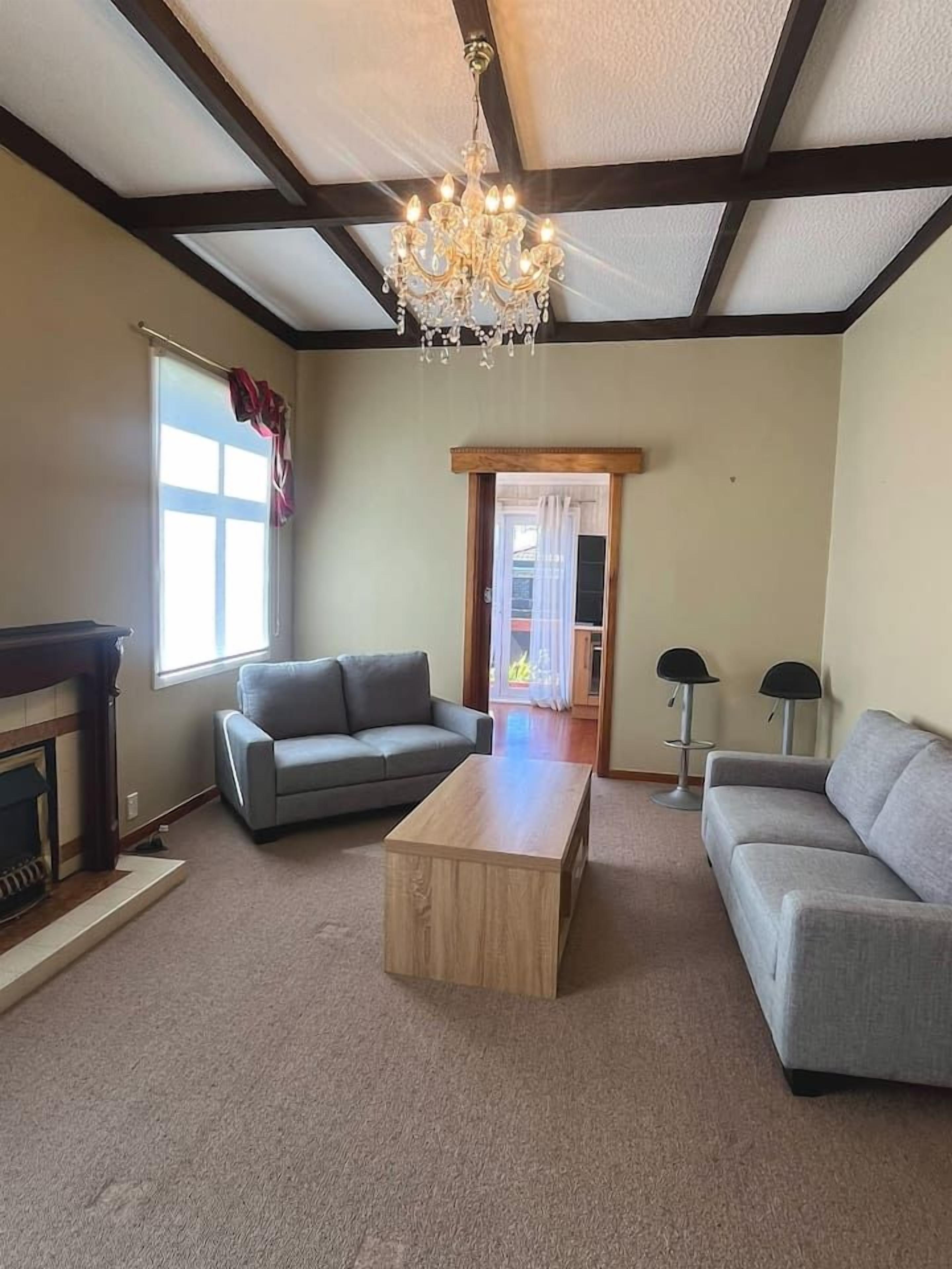 A living room with a fireplace, two sofas, a coffee table, and a chandelier.