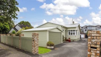 A single-story house with a garage, a fenced yard, and a brick wall with a mailbox.