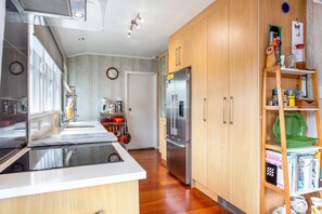 A modern kitchen with a stainless steel refrigerator, wooden cabinets, and a built-in oven.