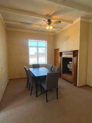 A room with a dining table, chairs, a ceiling fan, a window, and a built-in cabinet.