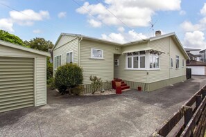 A two-story mobile home with a covered porch and a small garden area.