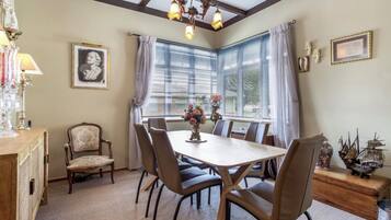 A dining area with a wooden table and chairs, a chandelier, and a window with curtains.